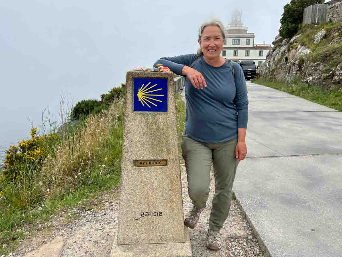 Camino de Santiago Finesterre mile marker 0. with woman hiker